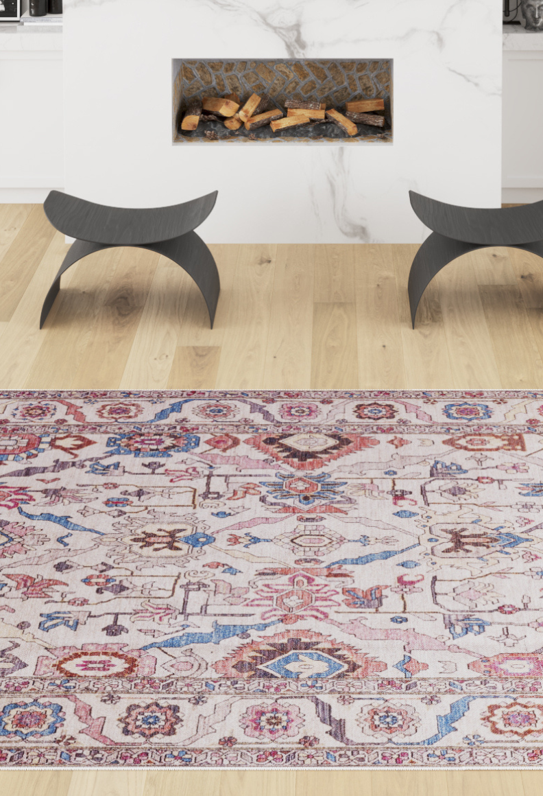 A living room scene featuring the Quasar Traditional Washable Rug - LCC3024 in red, blue, and beige on a light wood floor, flanked by two modern black stools and a white fireplace with stacked wood inside.