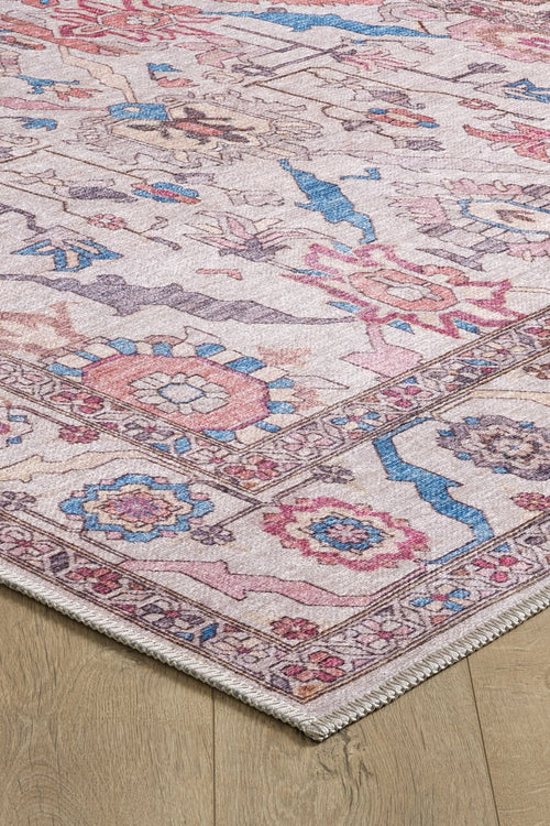 Load image 1 in gallery view. A close-up of the Quasar Traditional Washable Rug - LCC3024, a pastel flat weave with pink, blue, and beige floral and geometric patterns, shown on light wood flooring.