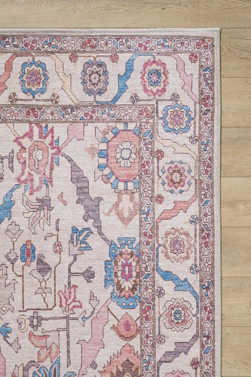 Load image 1 in gallery view. A close-up shows the corner of the Quasar Traditional Washable Rug - LCC3024 (Custom Size), featuring pink, blue, and beige floral and geometric patterns. Ideal for high-traffic areas, it's displayed on a light wooden floor.
