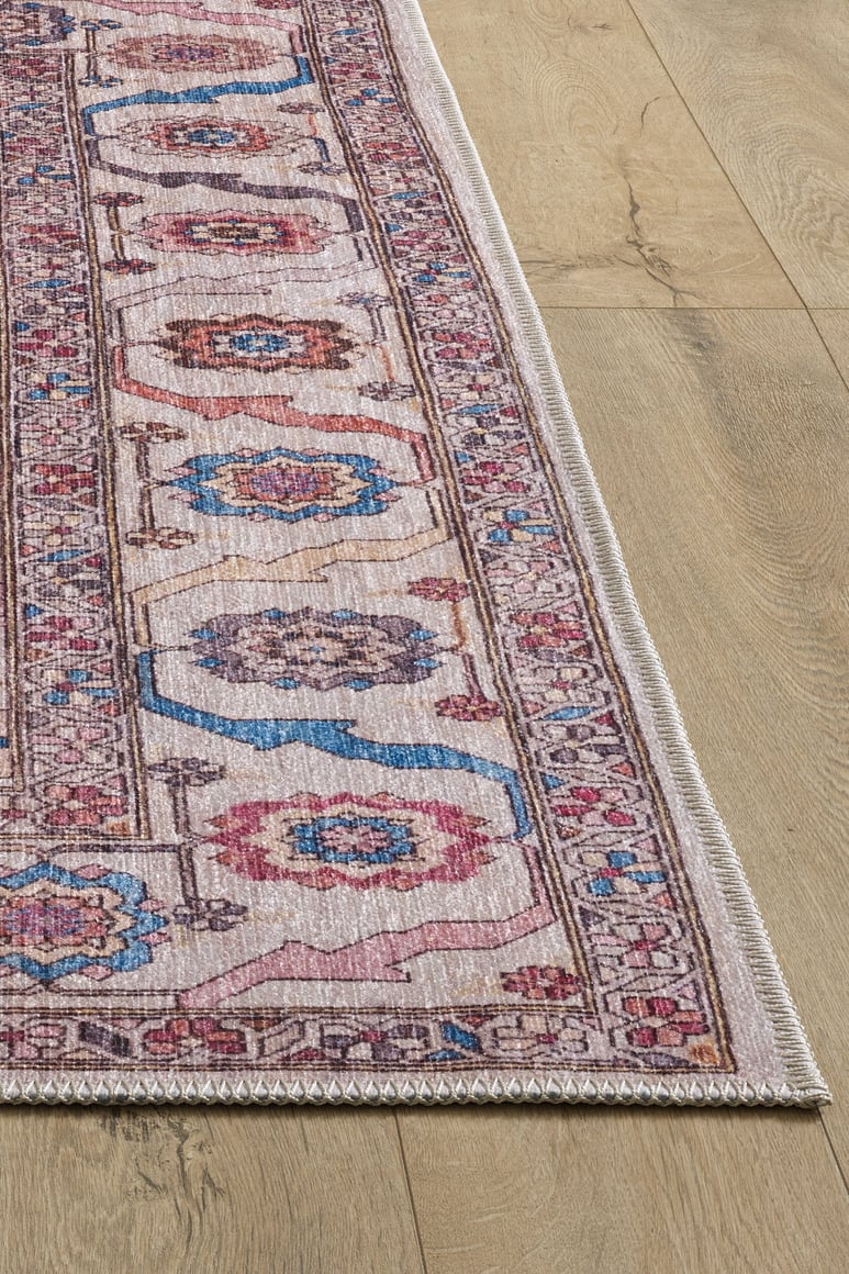 A close-up of the Quasar Traditional Washable Rug - LCC3024 (Custom Size) with pink, blue, and beige geometric and floral motifs on a light wooden floor—an ideal choice for high-traffic areas.