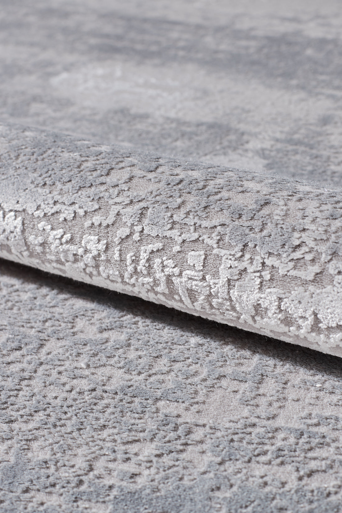 A close-up of the Radiant Edges Bordered Rug - Sapphire (M542I), featuring a light grey, machine-made design with a gently raised pattern, rolled edge, and soft, plush texture.