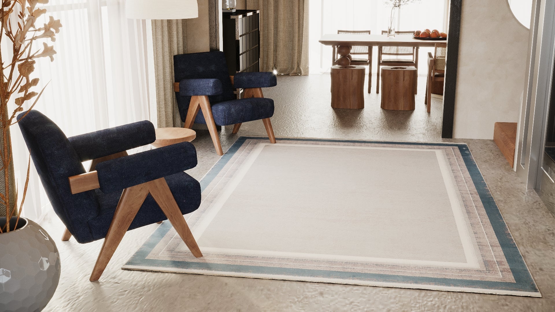 A modern living room with two dark blue armchairs on the Radiant Edges Bordered Rug - Sapphire - M542I, featuring wooden legs, a round side table, a gray vase with dried branches, and a dining area with wooden table and stools in the background.