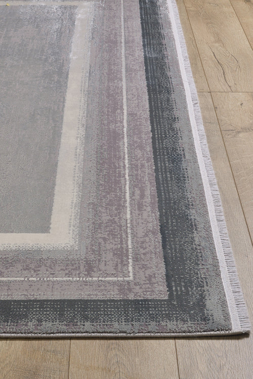 Load image 1 in gallery view. A close-up of the Radiant Edges Bordered Rug - Silver (M542B), featuring a geometric border in gray, beige, and purple tones, shown on a light wood floor.