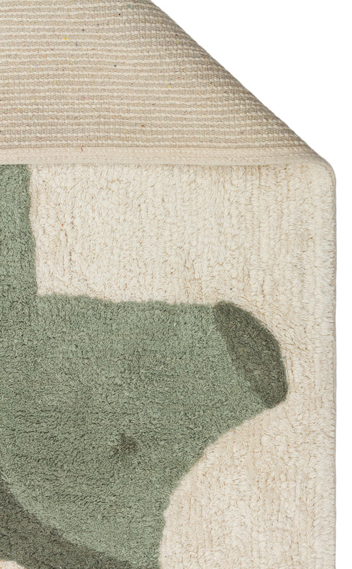 Load image 1 in gallery view. A close-up of the Rainbow Nap - Washable Shaggy - CBN08 kids playroom rug shows its green abstract design on a cream background, with a folded corner exposing the woven underside of this washable shaggy rug.
