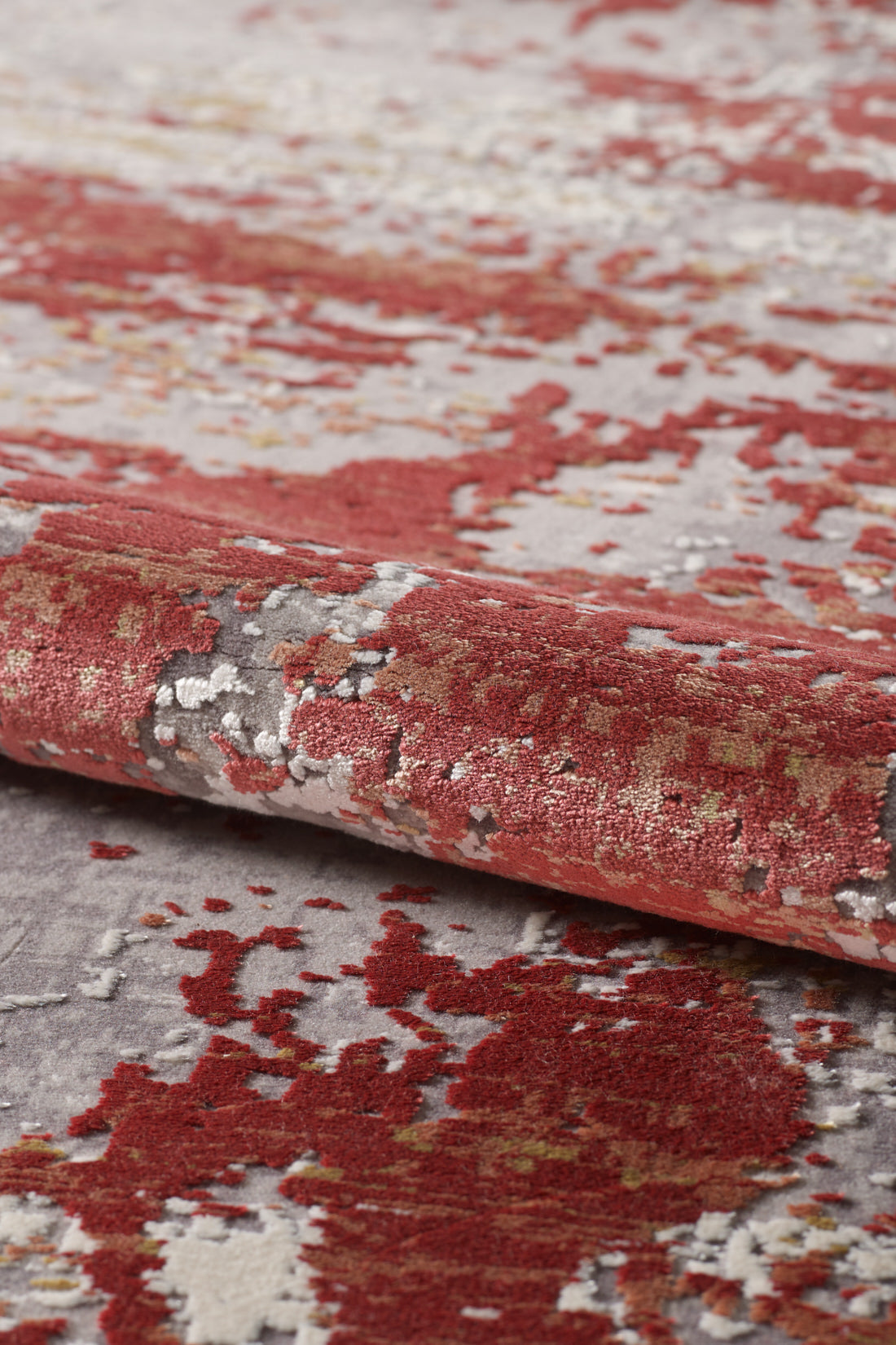 A close-up of the Red Strokes Premium Rug - 1052EB showcases its textured pattern in red, gray, white, and touches of gold, emphasizing the soft fibers and vibrant color blend across its surface.