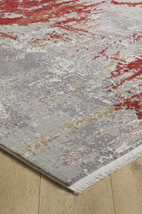 A close-up of the Red Strokes Premium Rug - 1052EB, a machine-made acrylic-viscose blend in gray, white, red, and yellow tones on a light wood floor; features a textured surface and finished edges with visible fibers.