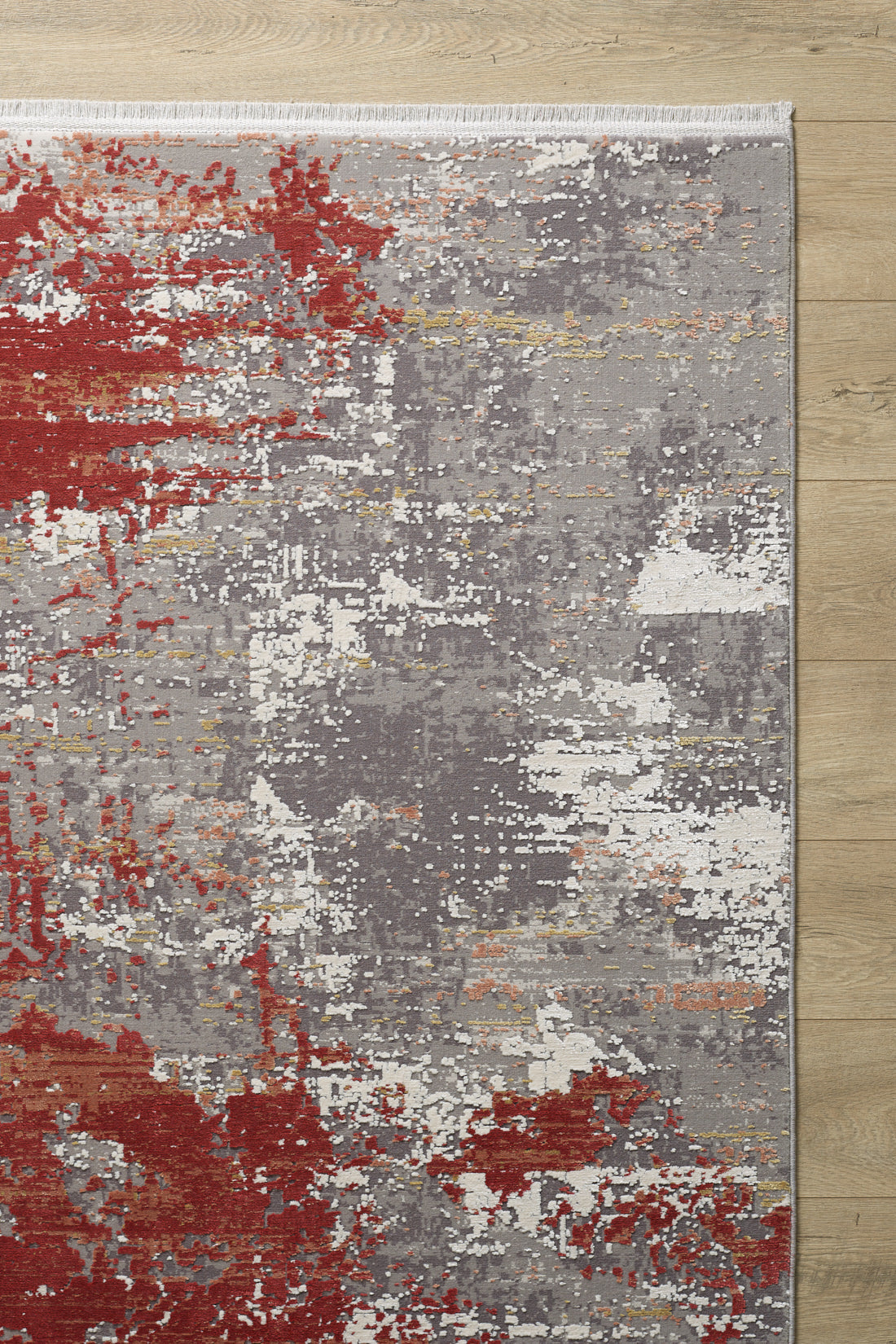 The Red Strokes Premium Rug - 1052EB features modern abstract designs in red, gray, white, and orange on high-quality acrylic-viscose. It rests on a light wood floor with a short white fringe along the upper edge.