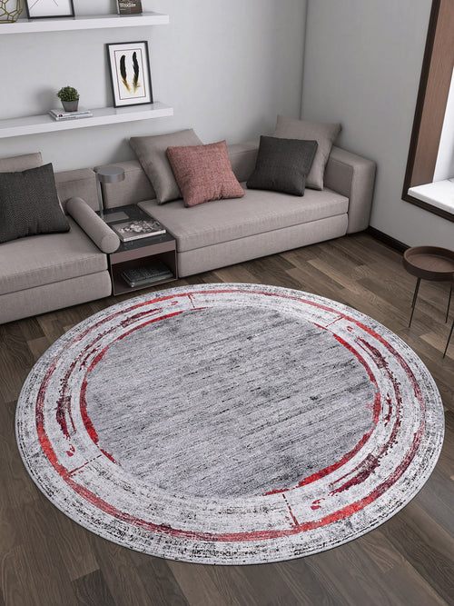Load image 1 in gallery view. A modern living room with a gray sectional, throw pillows, a round side table, and the Refined and Timeless - Washable Rug - JR1500—gray center with red/white circles—on dark wood floors. Decor shelves line the back wall.