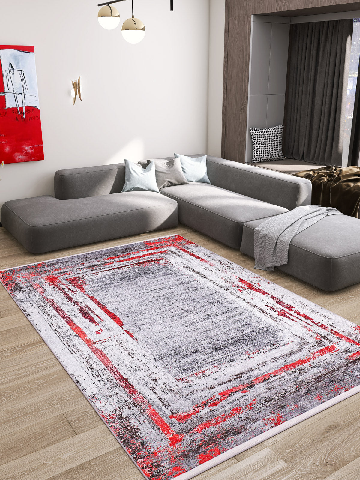 Modern living room with a large gray sectional, light wood floors, and the Refined and Timeless - Washable Rug - JR1500 featuring red accents—ideal for high-traffic areas. Abstract red-gray art adds flair; sunlight pours in from a nearby window.