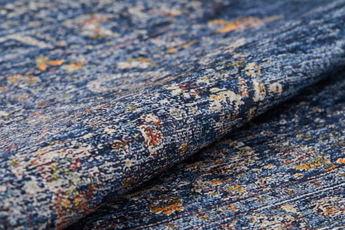 Load image 1 in gallery view. A close-up of the Regal Splendor - Washable Rug - JR1017 (Custom Size) shows its blue base with yellow, orange, and white accents, highlighting detailed woven texture and a slight fold—perfectly designed for easy cleaning in high-traffic spaces.