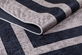 A close-up of the Regal Trellis - Washable Rug - JR601 (Custom Size) shows textured, velvety fabric with dark navy and light beige geometric patterns—ideal for high-traffic areas—with one corner neatly folded.