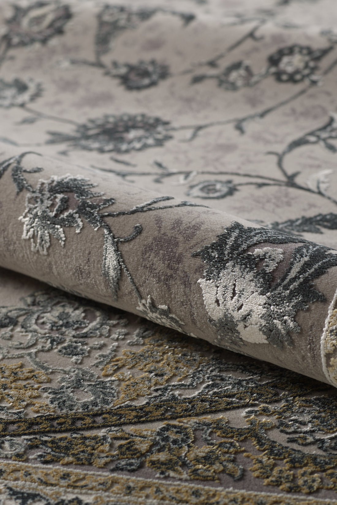 Close-up of the Reimagined Heritage Modernised Medallion Rug - Dust - M642B, a machine-made piece with an intricate floral and vine pattern in muted grey, beige, and yellow tones, plus raised textured detailing on the flowers.