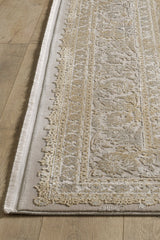 A close-up of the Reimagined Heritage Modernised Medallion Rug - Gold - M642F, featuring intricate beige and light brown patterns with fringed edges, displayed on a light wooden floor.