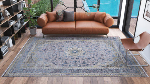 Load image 1 in gallery view. A modern living room with a tan leather sofa, decorative pillows, the Reimagined Heritage Modernised Medallion Rug - Sky - M642A, a brown chair, bookshelves, potted plants, and large windows overlooking a pool and garden.