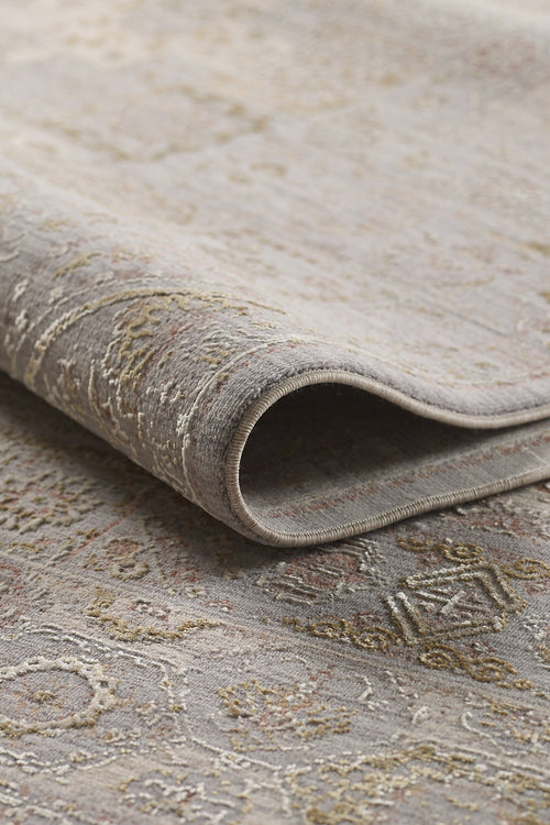 Load image 1 in gallery view. A close-up of the Revived Legacy Premium Rug - M616M, folded to showcase its intricate machine-made patterns in muted gray, beige, and gold tones with a detailed texture and soft woven surface.