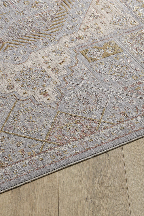 Load image 1 in gallery view. A close-up of the Revived Legacy Premium Rug - M616M, a viscose polyester piece with muted geometric patterns in light gray, beige, and gold tones, featuring floral accents and displayed on a light wood floor.