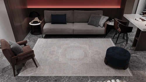 Load image 1 in gallery view. A modern living room with gray marble floors, the Revived Legacy Premium Rug - M616M, a gray sofa with cushions, a brown armchair, a round blue ottoman, and a small black side table against dark wood wall panels and soft lighting.