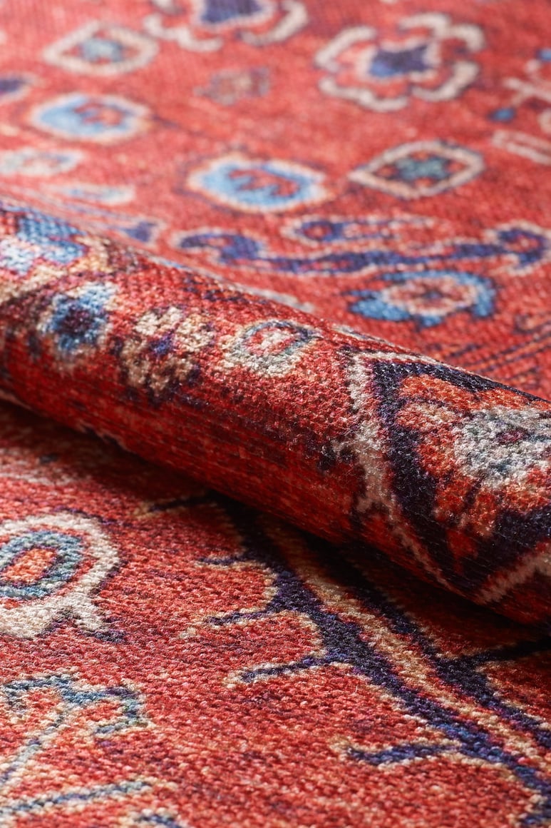 A close-up of the Rhapsody Authentic Red Washable Rug - LCC3033 (Custom Size) reveals its intricate woven designs and textured fibers in red, blue, and white—perfect for high-traffic areas and easy to clean.