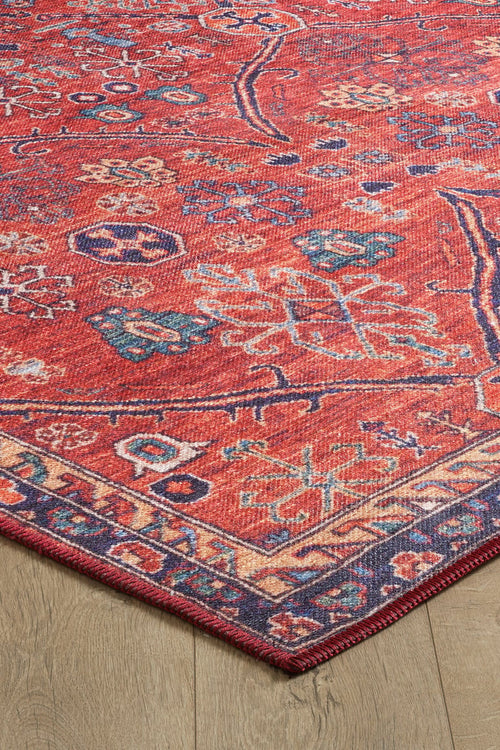 Bild 1 in Galerieansicht laden. A close-up of the Rhapsody Authentic Red Washable Rug - LCC3033 (Custom Size), featuring intricate multicolor patterns and a geometric border on a light wood floor. Its visible corner highlights its durability, ideal for high-traffic areas.