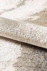 Close-up of the Riverstone Reflections Premium Area Rug - M685L, featuring detailed fibers and a textured, rolled-up acrylic-viscose surface with an abstract beige, cream, and light brown pattern.