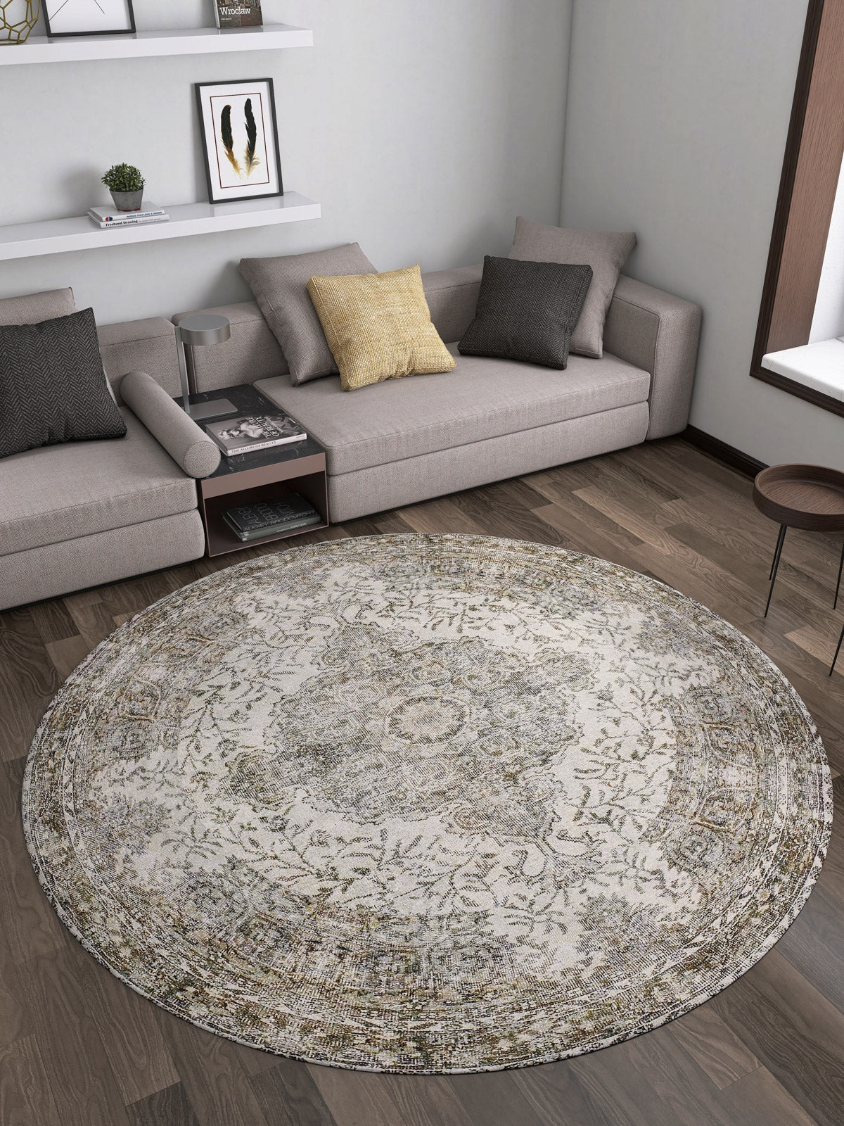 A modern living room features gray sectionals, a yellow accent pillow, wall shelves, dark wood flooring, and the Royal Legacy - Washable Rug - JR207 (Custom Size), ideal for high-traffic areas. A small round table and window complete the space.