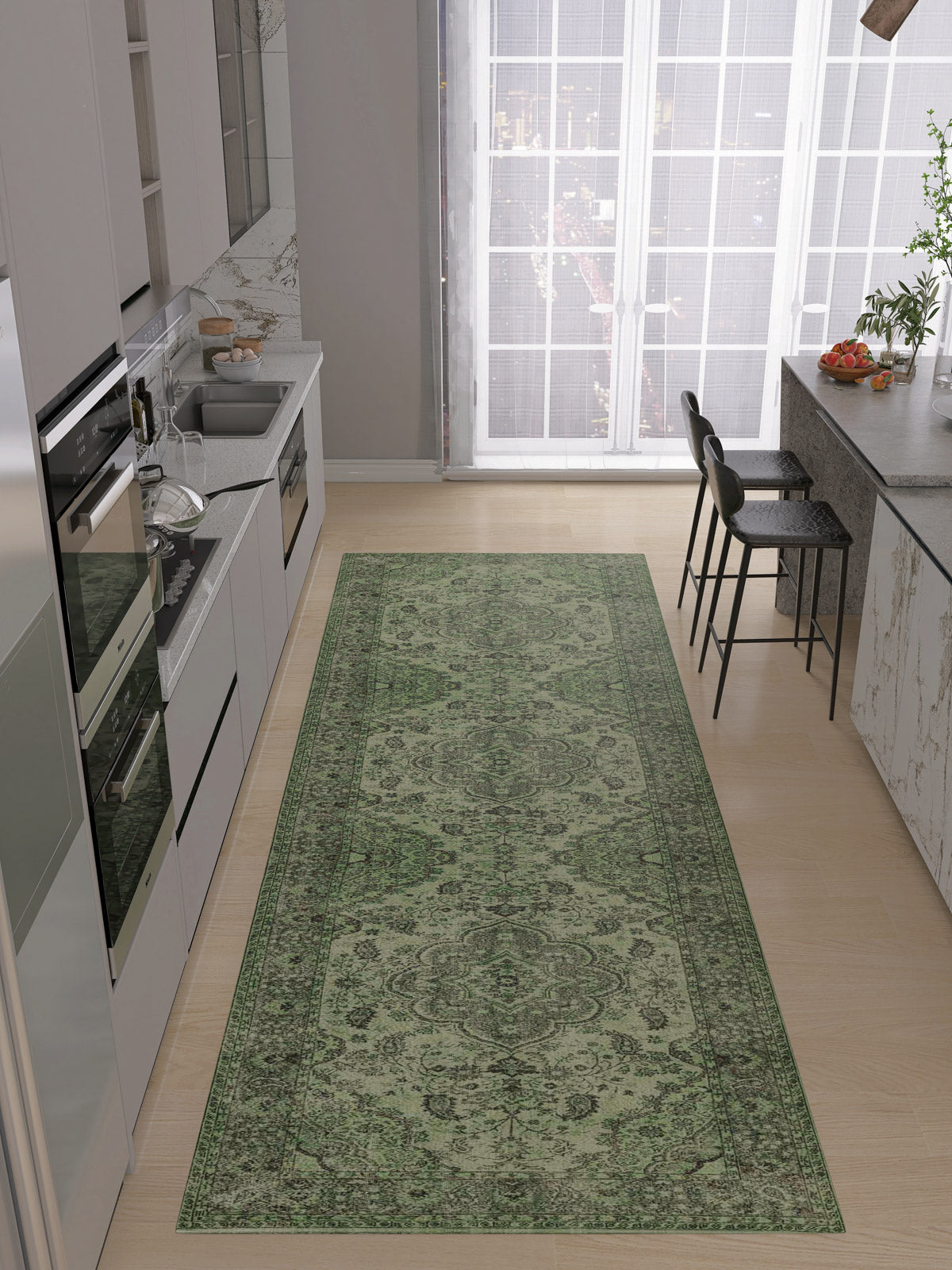 A modern kitchen with light wood floors features the Royal Vinework - Washable Rug - JRN1009 in green. White cabinets, built-in appliances, a sink, and a breakfast bar with two black stools sit by large windows.