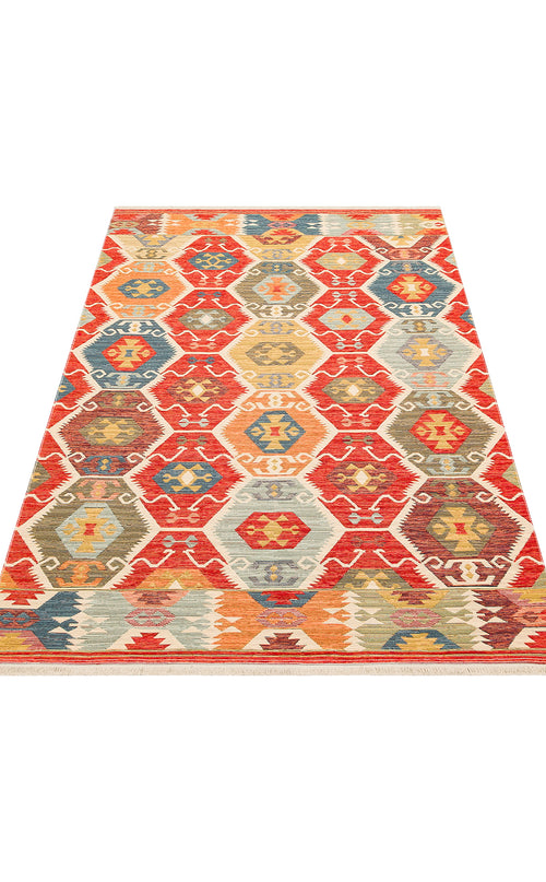 Load image 1 in gallery view. The Ruby Grain - Kilim - NMD06 is a flatwoven polyester area rug with a geometric tribal pattern of hexagons and diamonds in red, orange, blue, yellow, and cream tones, shown from a low angle.