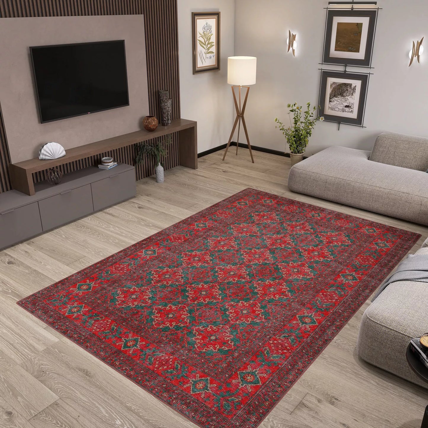 A modern living room with light wood floors, gray furniture, plants, wall art, and a Ruby Medallion - Washable Rug - JRN1031 (Custom Size) featuring a red pattern—ideal for high-traffic areas—centered in the space beneath a sleek media console and TV.