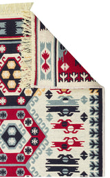 A close-up of the Ruby Weft - Washable Double-Sided Kilims - AR30 shows geometric and floral patterns in red, navy, yellow, and light blue. The folded corner reveals fringed edges and the reverse side's design.