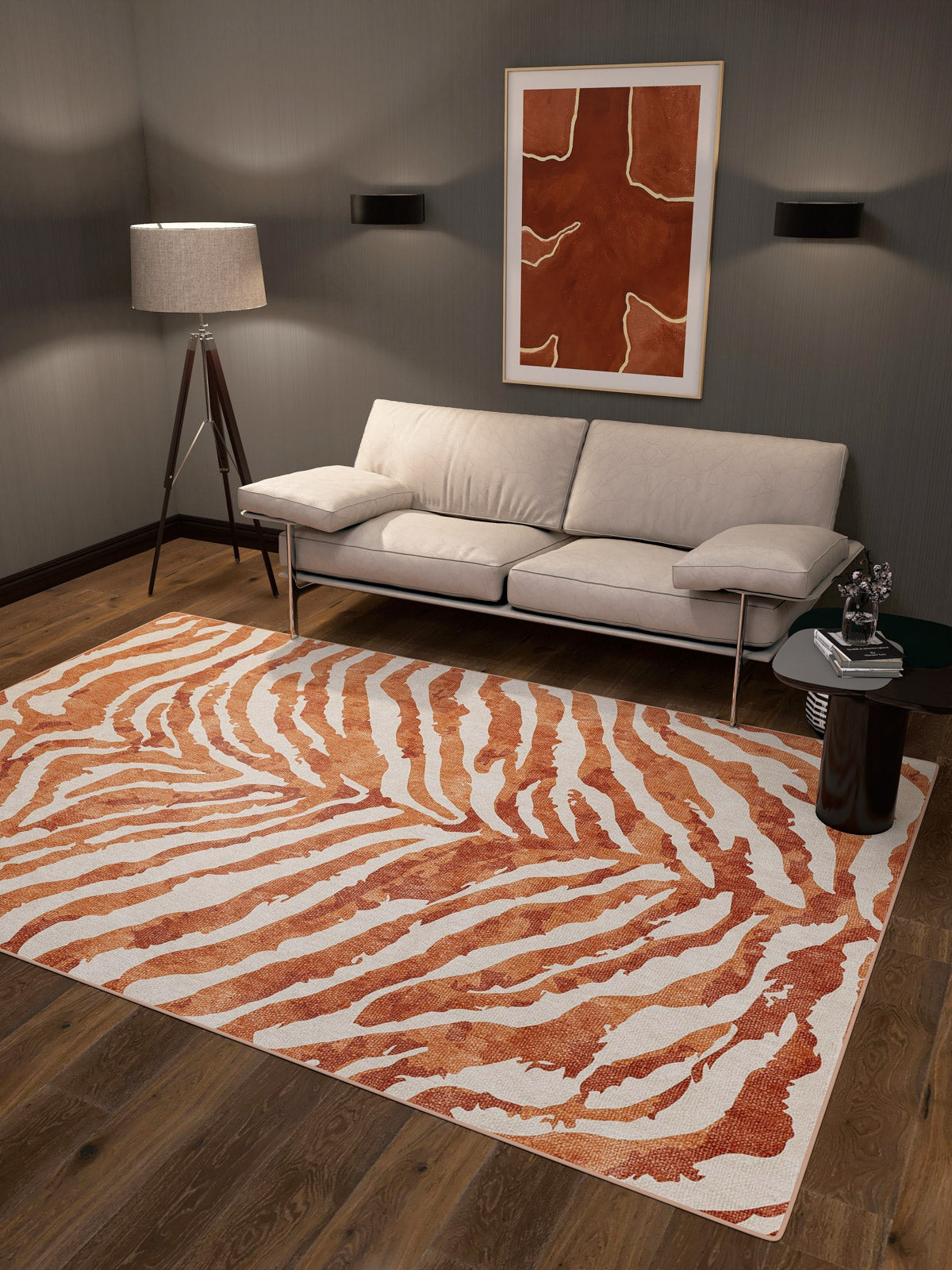 A modern living room features a white sofa, floor lamp, and side table. The Rustic Mirage - Washable Rug - JRN40 (Custom Size) adds bold orange-and-white zebra stripes, ideal for high-traffic areas. Abstract art decorates the gray wall above the sofa.