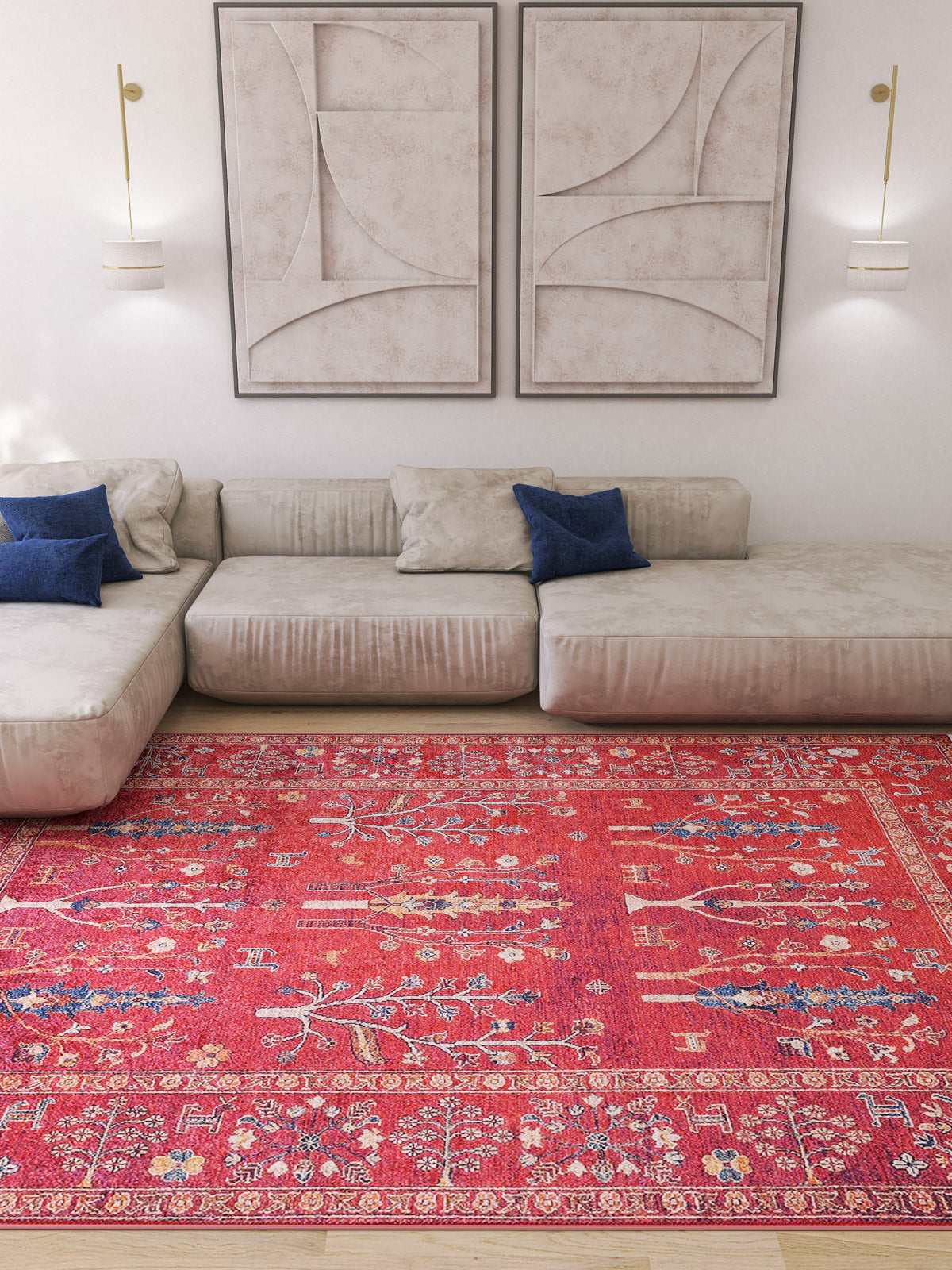 A modern living room with a light beige sectional sofa, blue accent pillows, the Rustic Retreat - Washable Rug - JR5095 in bright red for high-traffic areas, two abstract wall art pieces, and wall-mounted lights on a white wall.