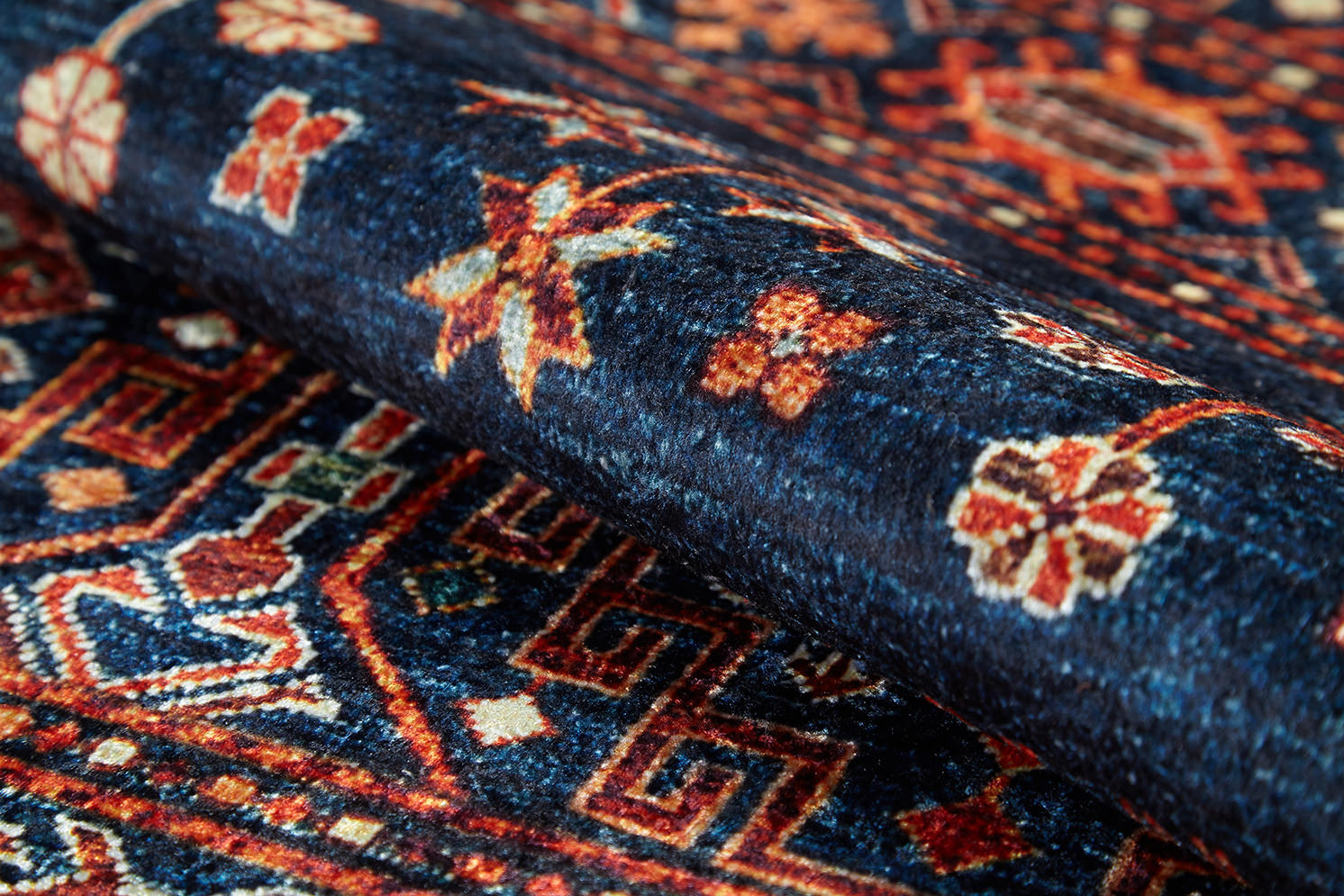 Close-up of the Sahara Sunrise - Washable Rug - JR5091 (Custom Size), showcasing its rolled form with intricate floral and geometric patterns in deep blue, red, white, and orange—perfect for allergy-sensitive spaces.