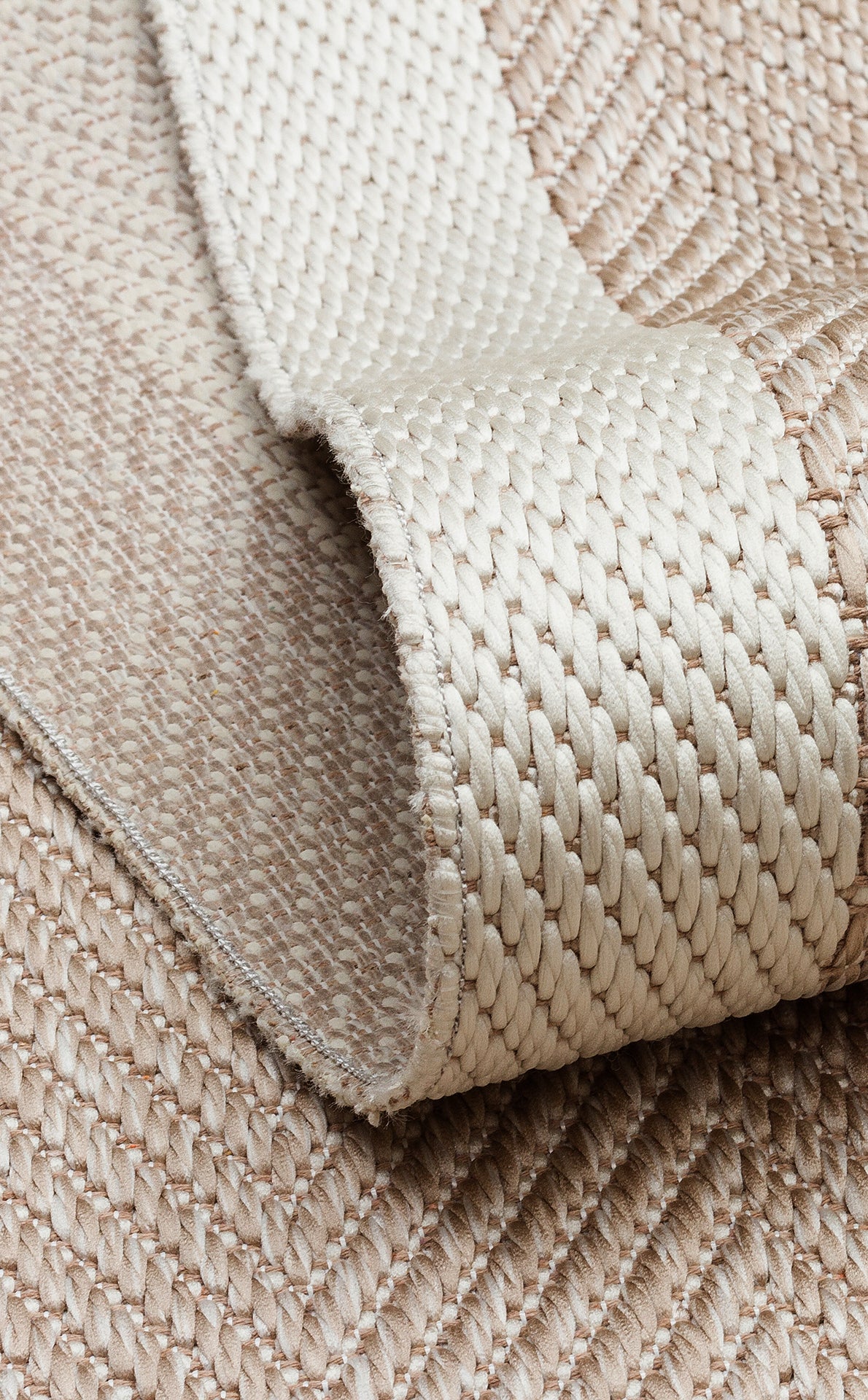 Close-up of the Sand Drift - Kilim - MNO02 flatwoven polyester rug in beige and cream, showing its folded edge and detailed woven patterns.