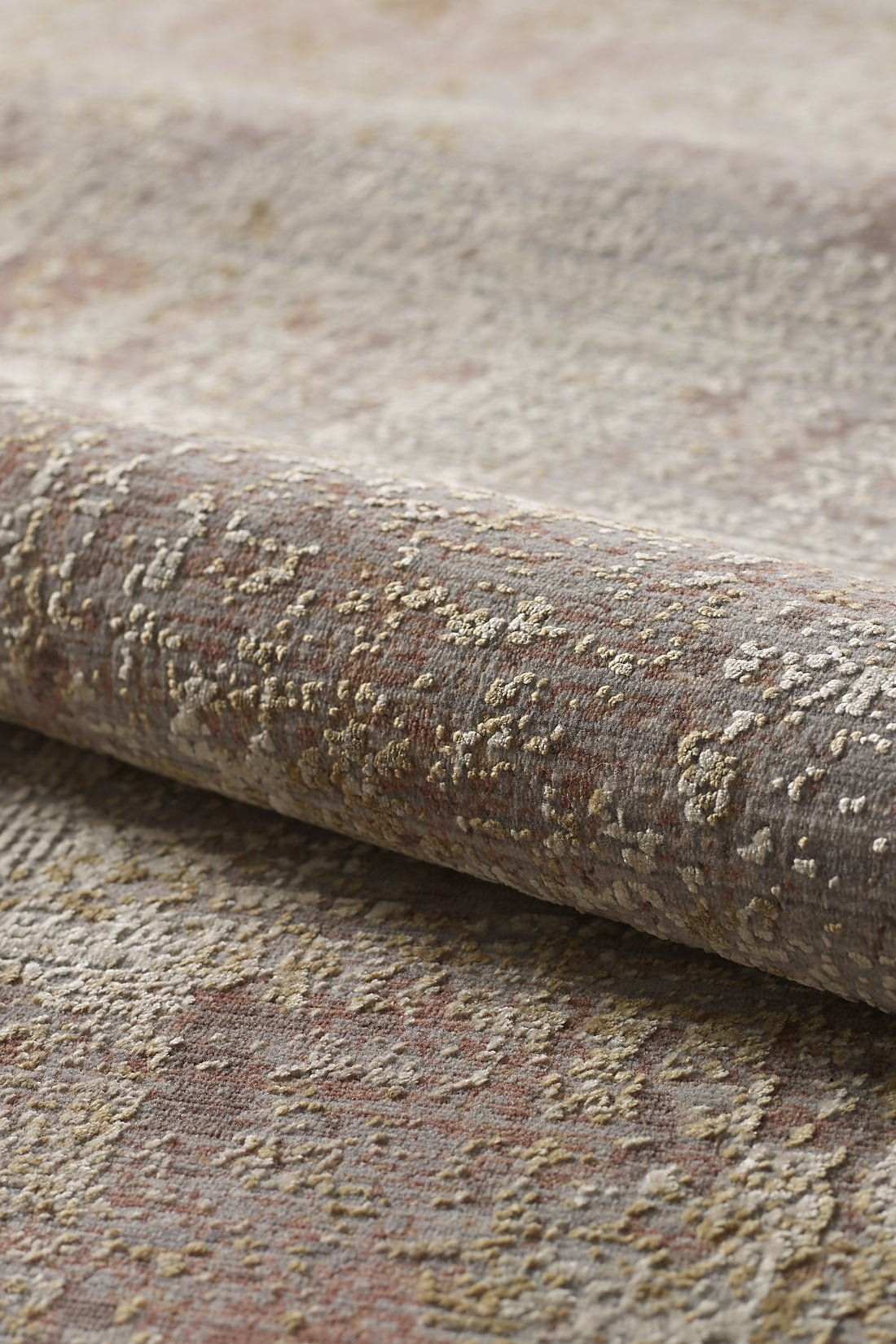 Close-up of the Sandy Whisper Neutral Rug - M628M, a high-end machine-made roll featuring a mottled pattern in beige, gray, reddish-brown, and gold. Its soft surface has a raised, slightly uneven texture.