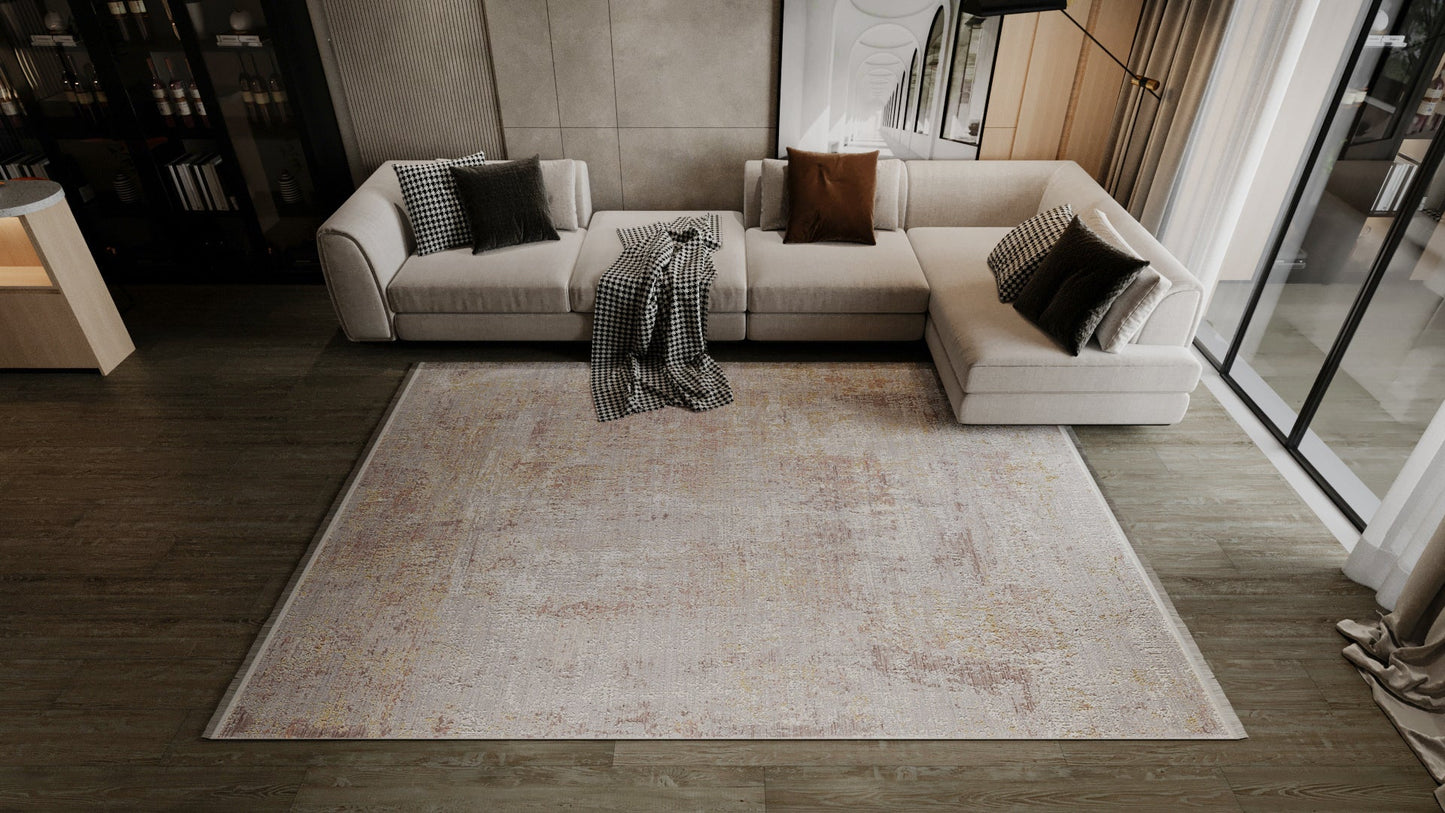 A modern living room with a light L-shaped sofa, brown and checkered cushions, a blanket, wood flooring, floor-to-ceiling windows with sheer curtains, and the Sandy Whisper Neutral Rug - M628M.