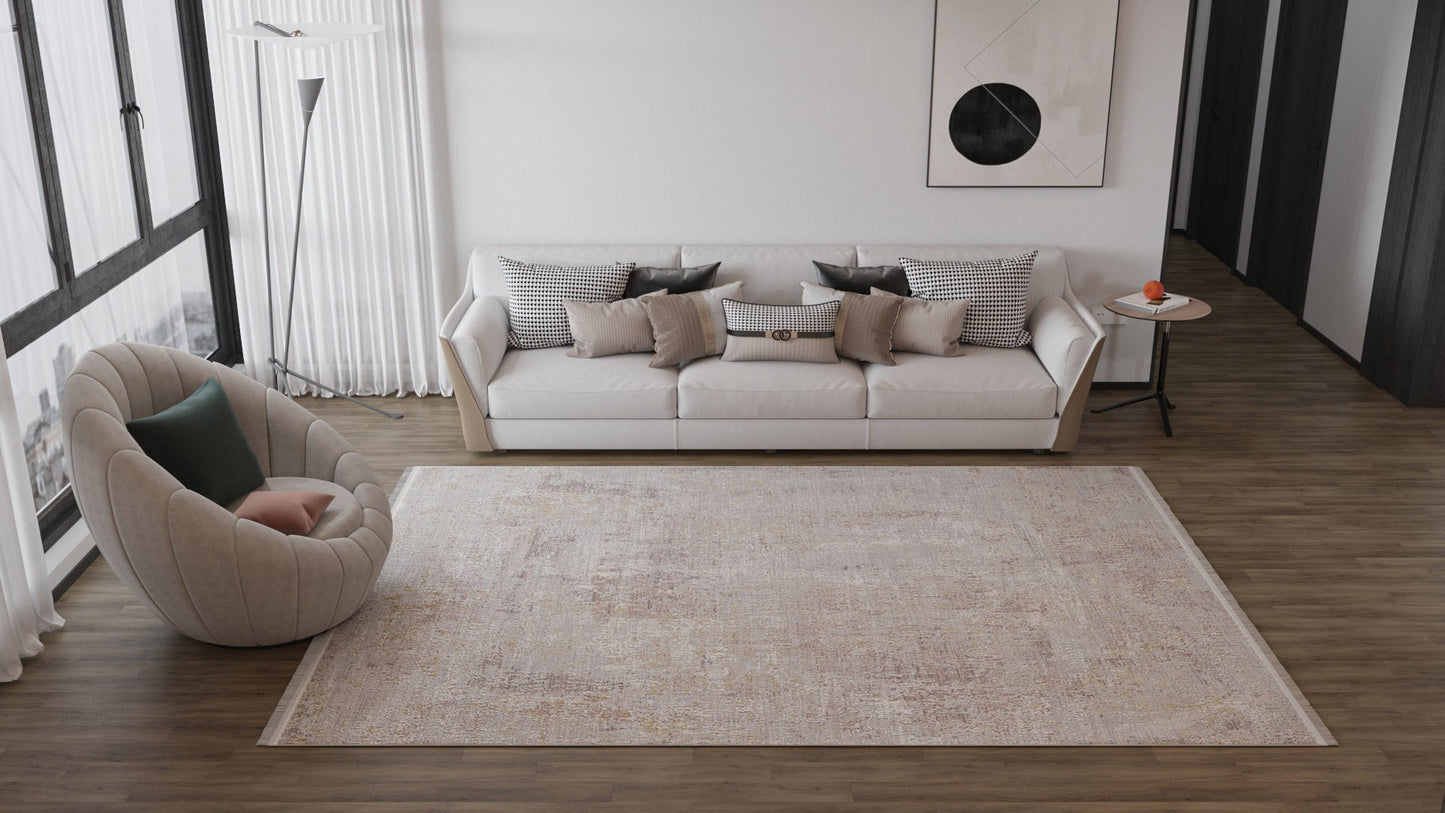 A modern living room with a large Sandy Whisper Neutral Rug - M628M, a white sofa with assorted pillows, a round armchair with a green cushion, a side table featuring an orange object, and abstract art adorning the wall.