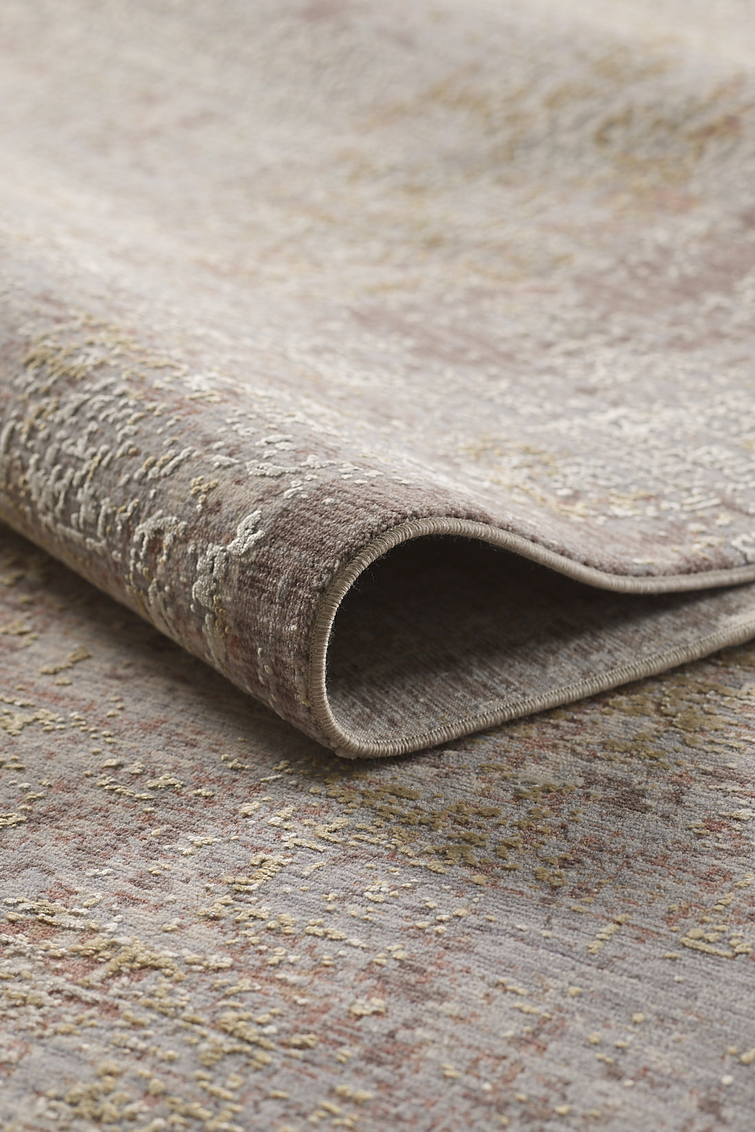 A close-up of the Sandy Whisper Neutral Rug - M628M shows its soft, textured surface in muted beige, taupe, and light gold tones with subtle patterns and a gently distressed vintage look.