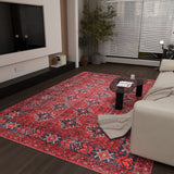A modern living room featuring the Scarlet Charm - Washable Rug - JRN1032, perfect for high-traffic areas, a light sofa with a beige throw, black oval coffee table, wall-mounted TV, and a potted plant beside window blinds.