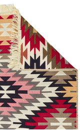 Scarlet Path - Washable Double-Sided Kilims - AR33 features geometric zigzag patterns in red, black, cream, beige, and pink. A folded corner reveals its fringed edge and reversible design.