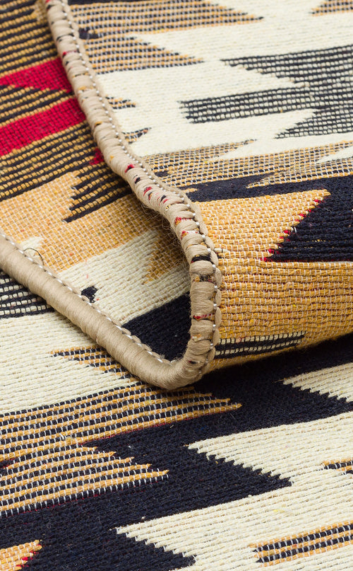 Load image 1 in gallery view. A close-up of the Scarlet Path - Washable Double-Sided Kilims - AR33 rug displays a bold black, gold, red, and cream geometric pattern with hand-stitched binding revealed along the folded edge.