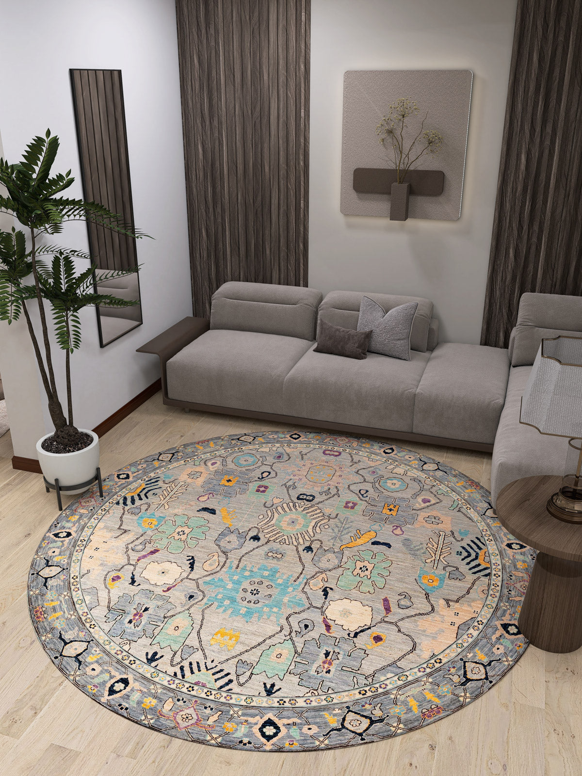A modern living room with a gray sectional, Seraphix Pastel Bordered Washable Rug - LCC3011 for high-traffic areas, pastel hues, a potted plant, wooden accents, wall décor, and a small round side table on light wood flooring.