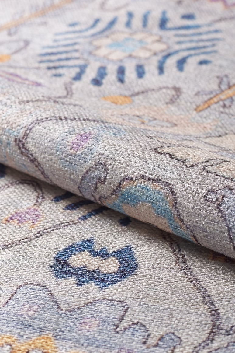 A close-up of the Seraphix Pastel Bordered Washable Rug - LCC3011 highlights its soft, textured surface and intricate blue, grey, cream, and yellow floral-geometric design—ideal for high-traffic spaces.