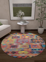 The Serene Sahara - Washable Rug - JR1959, with vibrant geometric patterns, adds color to a modern living room with dark wood floors. Ideal for high-traffic areas, it pairs well with a white sofa, side table, potted plant, and abstract wall art.