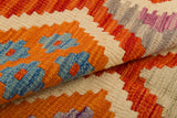 Close-up of the Silk Road - Handwoven Kilim (Outlet) US, showcasing vibrant geometric patterns in orange, cream, blue, red, and purple. The detailed flatweave texture and overlapping fabric layers are clearly visible.