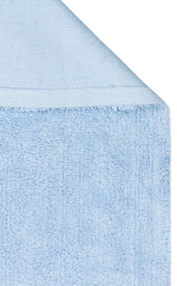 A close-up of the Sky Nap - Washable Shaggy - CBNPLAIN towel in light blue, highlighting its plush, textured fabric and tidy stitched edge, with a folded corner revealing both sides of the soft material.