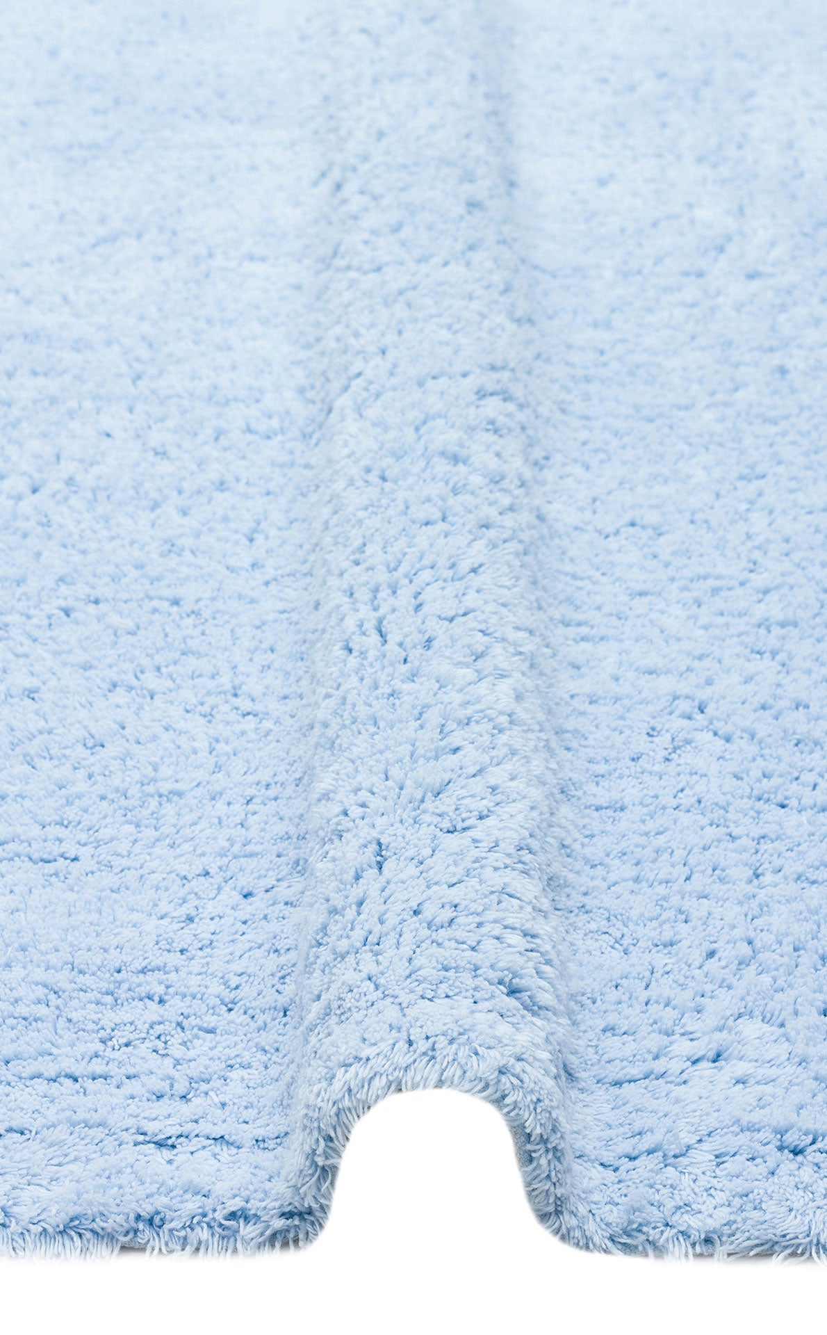 Close-up of the Sky Nap - Washable Shaggy - CBNPLAIN, a soft blue rug with a textured, fluffy surface and center contour to fit around your toilet base. This washable rug adds comfort and style to any bathroom.