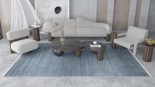 Load image 1 in gallery view. A modern living room with light beige sofas, dark wood tables, minimalist decor, and a Slate to Midnight Navy Rug (M497M) adds a contemporary touch alongside abstract wall art and dried plants in a vase on the coffee table.