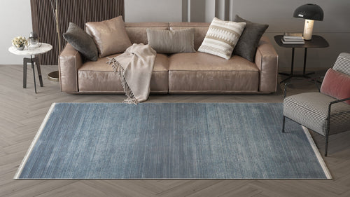 Load image 1 in gallery view. A modern living room featuring a beige leather sofa, neutral cushions, beige throw, striped armchair, dark side table with lamp, and the Slate to Midnight Navy Rug - M497M on light herringbone wood flooring.