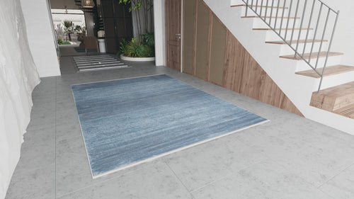 Load image 1 in gallery view. Modern entryway with large gray tiles, the Slate to Midnight Navy Rug (M497M), wooden stairs with metal railings, wood-paneled closet doors, and indoor plants by the staircase. Natural light fills the space.