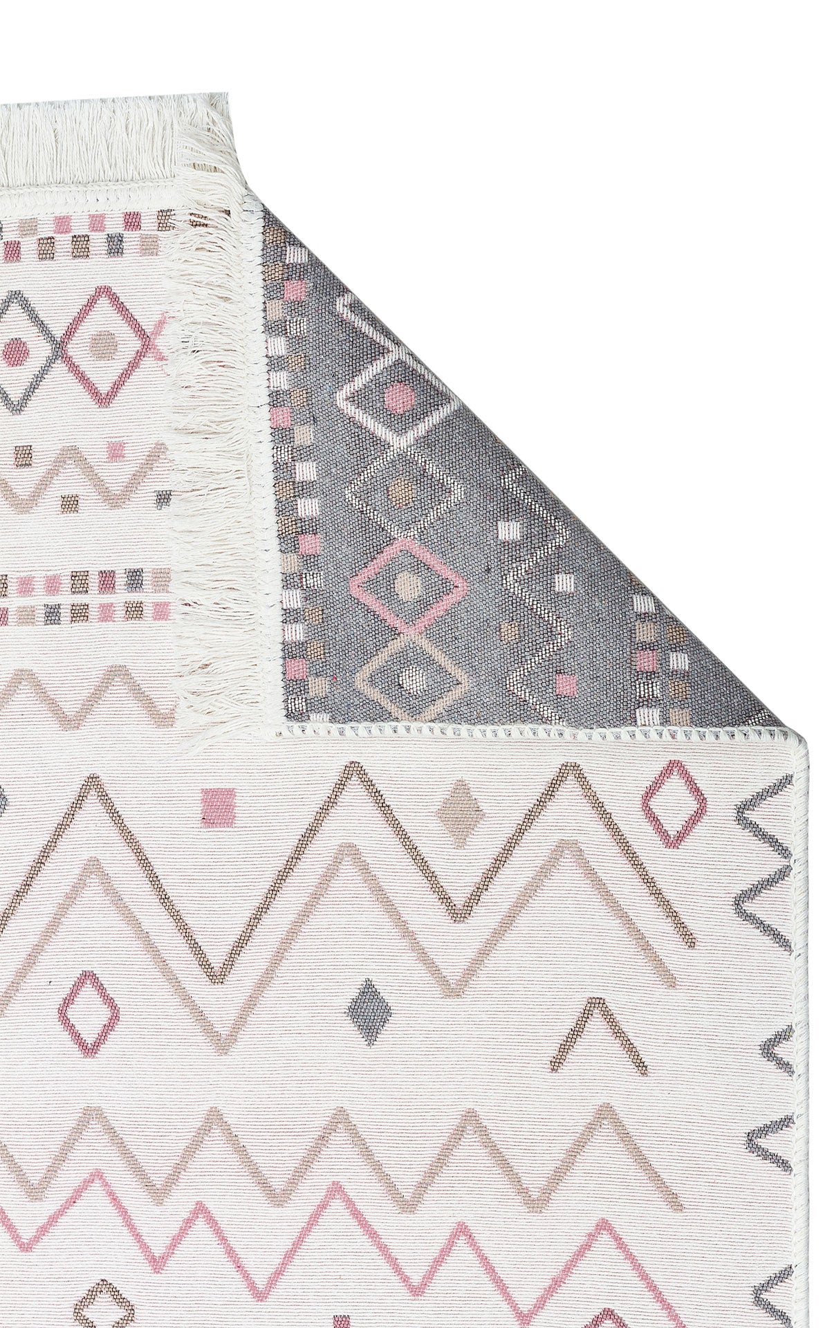 A close-up of Soft Bloom - Washable Reversible Kilims - AR05 rug displays geometric patterns in pink, beige, and gray. One corner is folded, revealing the contrasting gray underside with matching geometric designs.